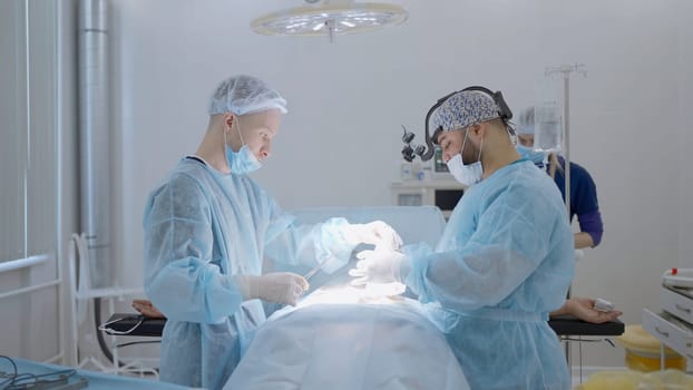 Surgeons during operation at the hospital. Action. Medical nurse is helping, arranging instruments