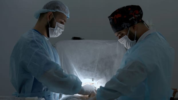 Surgeons working in operating room at a hospital. Action. Two male doctors at work