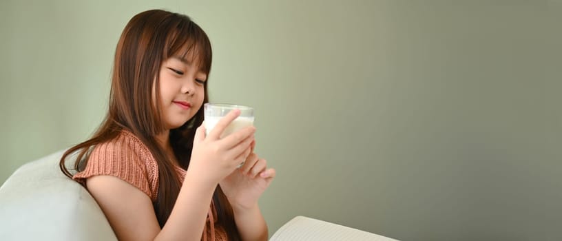 Cheerful little Asian girl drinking milk for energy vitamins or health calcium source.