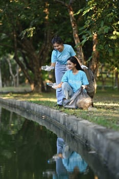 Shot of young volunteer women collecting trash in the park. Environmental protection and charity concept.