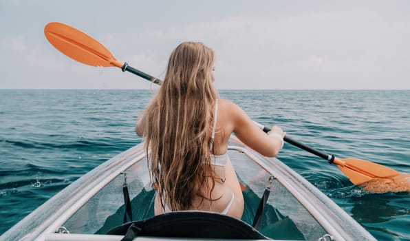 Woman in kayak back view. Happy young woman with long hair floating in transparent kayak on the crystal clear sea. Summer holiday vacation and cheerful female people having fun on the boat.