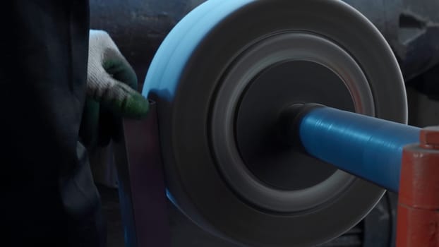 Close up of grinding machine with spinning fast polishing disk. Creative. Metal details production on factory. Manufacturing, industrial and technology concept