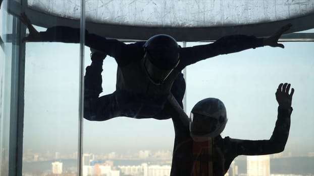 Male instructor helps man to fly inside air-tube. Training flight in an air tube with an instructor.