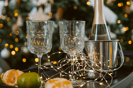 Champagne glasses, New Year decor. New Year's festive setting, family holidays.Two glasses of champagne are on the table against the background of New Year's decorated tree