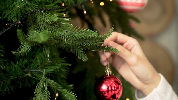 Close-up of woman's hand hanging Christmas toy. Decorating Christmas tree. New year and Christmas holidays concept.