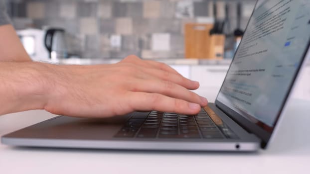 Side view of a man using laptop and typing on keyboard. Close up of male hands typing a letter while working at home on his computer, concept of freelance.