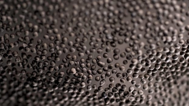 Black peppercorn background, grains lying on glass surface. Close up of black pepper seeds as texture, organic food, healthy lifestyle and diet concept.