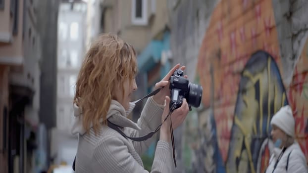 A pretty woman photographer. Action.A tourist walking around a big city with sobbing hair taking photos next to graffiti. High quality 4k footage