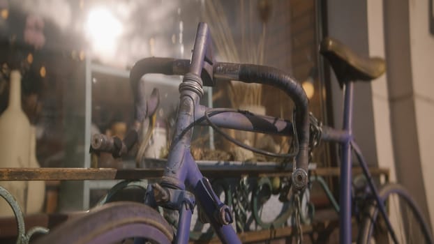 Vintage bicycle with chain at store. Action. Antique bicycle stands at window of store. Old rusty bicycle stands outside building on sunny day.