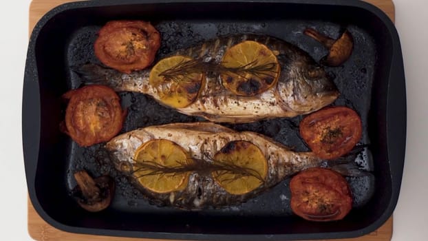 Top view of process of cooking fish. Close up of raw fish being cut, salted and spicied, ant then grilled with mushrooms, tomatoes and slices of orange, healthy food concept.