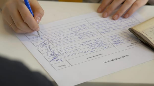 Man signing a document or writing correspondence with a close up view of his hand with the pen.