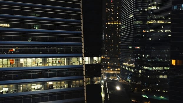 View of a city skyline with skyscrapers in the foreground at night. Shot. Top view of high-rise buildings in center of metropolis at night.