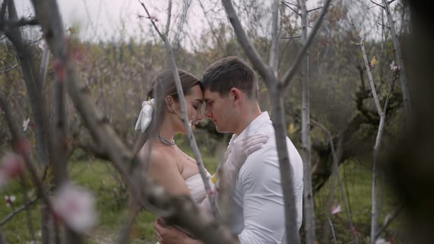 Wedding photosession in a summer green garden. Action. Beautiful bride and groom loving couple posing together outdoors