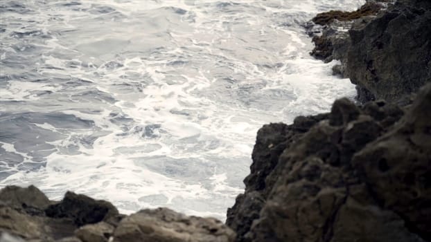 The waves fighting about the rocky ocean coast. Action. View of the raging waves of the sea breaking on the rocks.