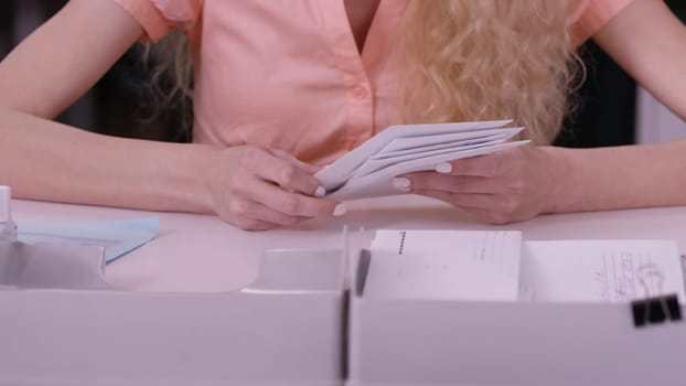 Woman's hands iterate over the letters in envelopes. Close up of envelopes being in hands of an aged woman. Secretary closing pile of envelopes.