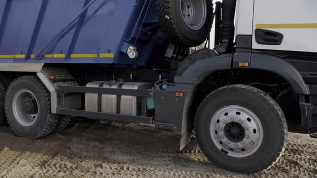 Close up of wheels of a slowly moving truck on sandy surface. Scene. Construction site background