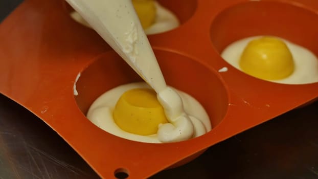 Pastry bag filling a flexible silicone mold with mousse. Gourmet French dessert, close-up.