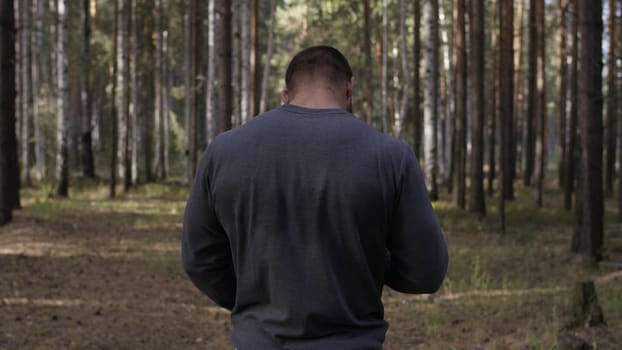 Rear view of fit young man with muscular build standing against sport ground background. Fighter looking at copy space. The muscular male back.