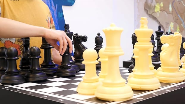 Close up for people playing giant chess, board games concept. Two classmates play big chess at a science activity centre.