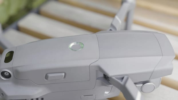 Close up of quadrocopter or drone details. Professional shooting equipment, grey quadcopter body with glowing indicator ready for flight.