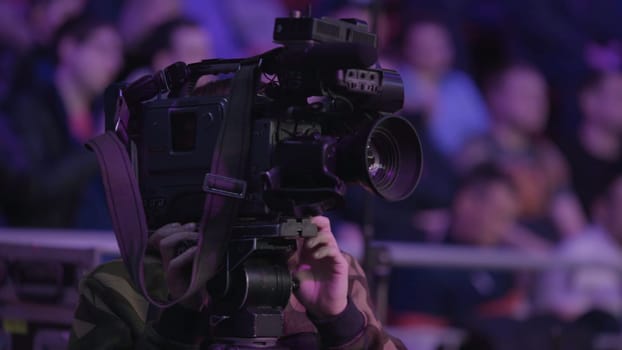 Cameraman using black professional digital video camera. Setup and working. Professional cameraman with headphones with camcorder in live television.