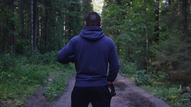 Person in a hood standing. Man in the hood in the woods. Sport in the forest on the nature.