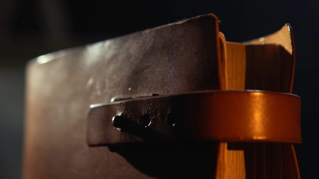 Close-up of old leather bound book with the leather straps in the dark room. Vintage books with leather bound, close-up.