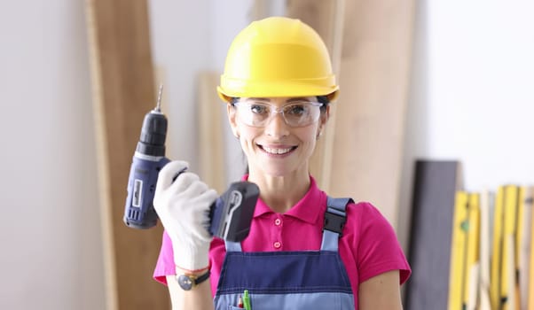Woman builder in protective helmet holding drill in her hands. Men's work for women concept