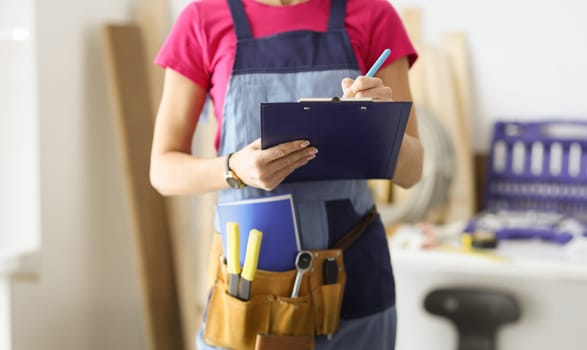 Woman repairman writing paper on clipboard closeup. Quality repair concept