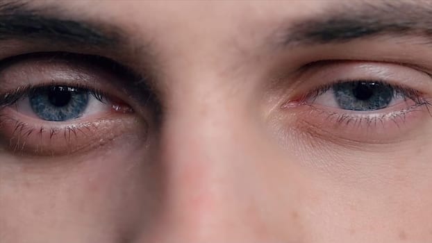 Closeup of young man's blue eyes with problematic skin acne and selective focus. Close-up portrait of a young man with blue eyes - OBS: model use lens contact. Human eye detail. Human eye close-up detail