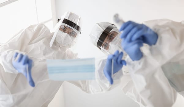 Doctors in protective suits putting mask on patient and measuring temperature. Security measures to combat covid19 concept