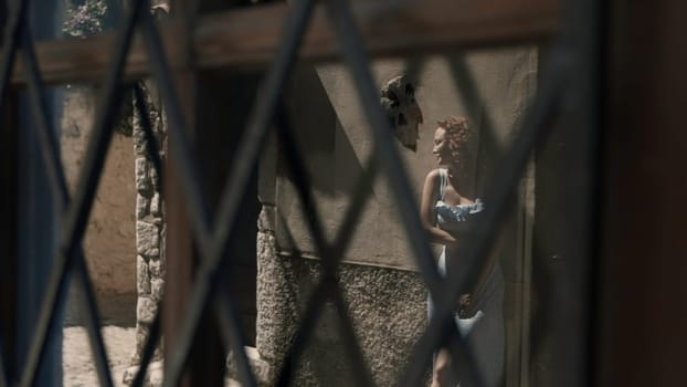 A woman posing behind an iron mesh. Action.Model with flowing hair is clinging to the wall and smiling. High quality 4k footage