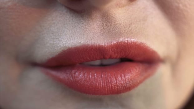 Close up of red sexy lips of a woman biting a green olive. Sensitive red lips, extreme close up of facial details of a young woman with beautiful skin.