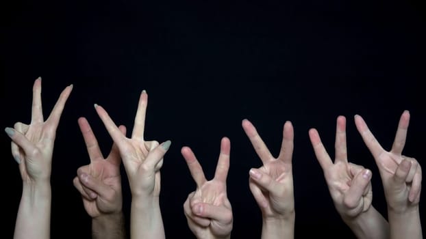 Crowd hands with sign of victory. Close-up of many hands with fists raised up then changed to sign of victory. Metaphor of war and peace.