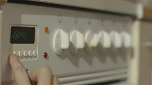 Female hand turning on white kitchen gas stove. Woman turn on the stove in the kitchen close up 4K