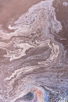 A marble texture of a rainbow spill of gasoline on a sidewalk in a puddle as a background.