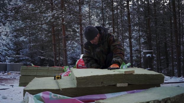 Men cutting building materials in winter forest. Clip. Man cuts materials for building house in forest in winter. Man prepares materials for building house in forest.