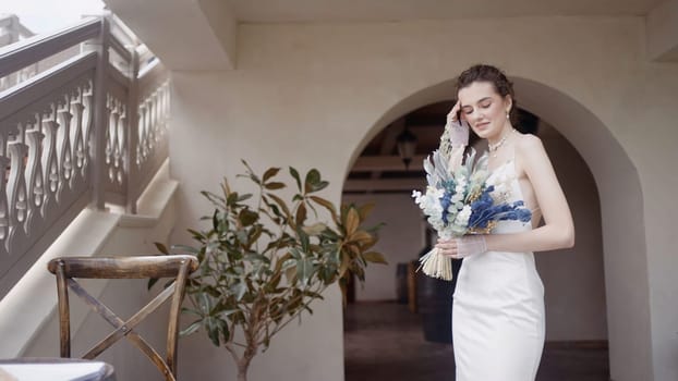 Wedding photography. Action. A beautiful white stone palace next to which the newlyweds do photo shoots where the bride in a long white dress with a bouquet and the groom hugs her