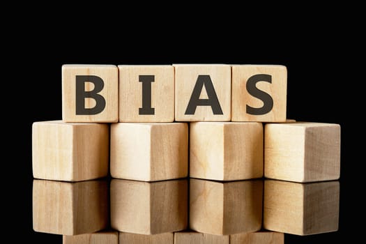 Bias text assembled from wooden cubes on a black background