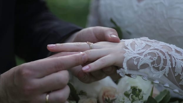 Bride wear ring on groom's finger. The groom puts the wedding ring to finger of the bride. marriage hands with rings. birde wears the ring on the finger of the groom HD