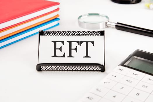 EFT text on a business card next to office supplies on a white background