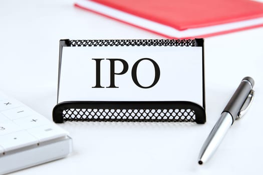 IPO abbreviation of Initial Public Offering the word on the business card standing on a stand next to a notepad, calculator and pen
