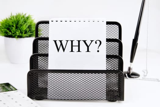 WHY A word written on a piece of paper from a notebook on a stand on a white background