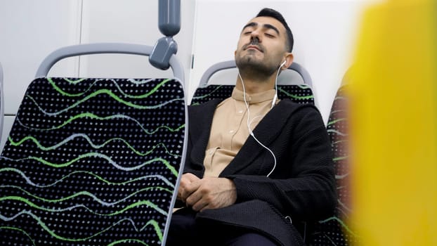 A man enjoying a ride. Media.A handsome man with stubble in office-style clothes rides a bus listening to music and sitting on the phone. High quality 4k footage