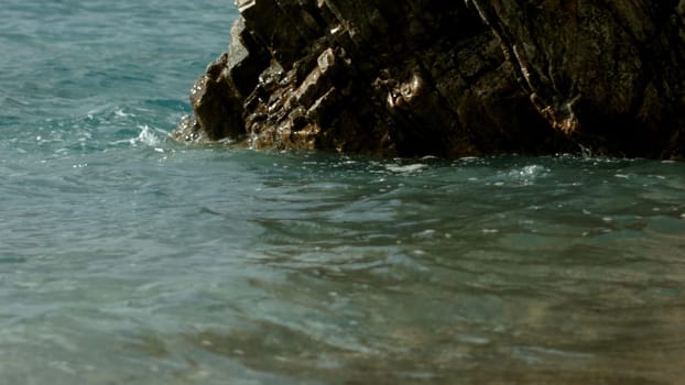 Smelling the sea. Creative.Waves of blue transparent sea beating against the stones where a bridge with walking tourists is visible. High quality FullHD footage