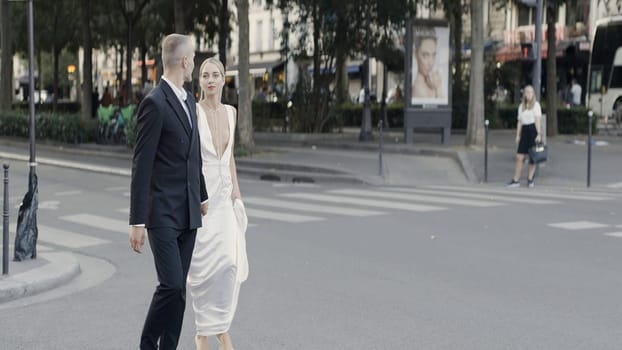A walking European couple on a summer street. Action. Newlyweds in suits walking on the roads in hot weather. High quality 4k footage