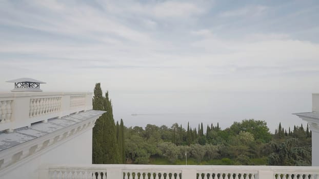 View from hotel's balcony to sea. Action. Roof of old hotel with columns on background of sea. View of sea and vegetation from roof of hotel.