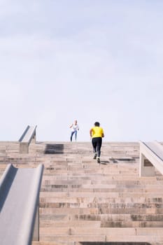 vertical photo of a sports senior man training on stairs while receiving encouragement from personal trainer, concept of active and healthy lifestyle in middle age, copy space for text