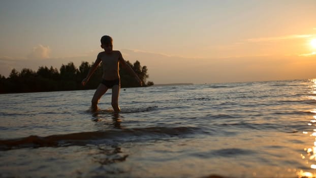 Stunning natural background with sunset above the sea. Creative. Little boy playing in water
