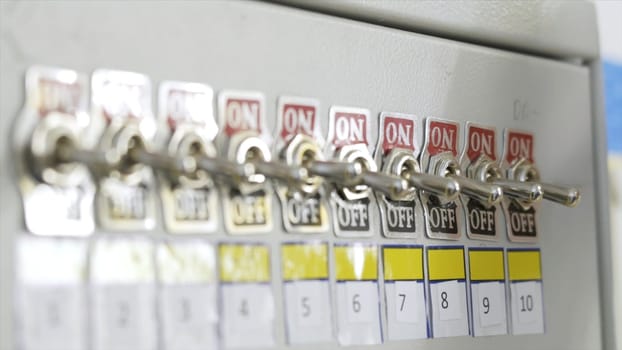 Close-up of fuse switch panel. Action. Manual panel with toggle switches on factory fuse. Hand of factory worker switches toggle on brush.